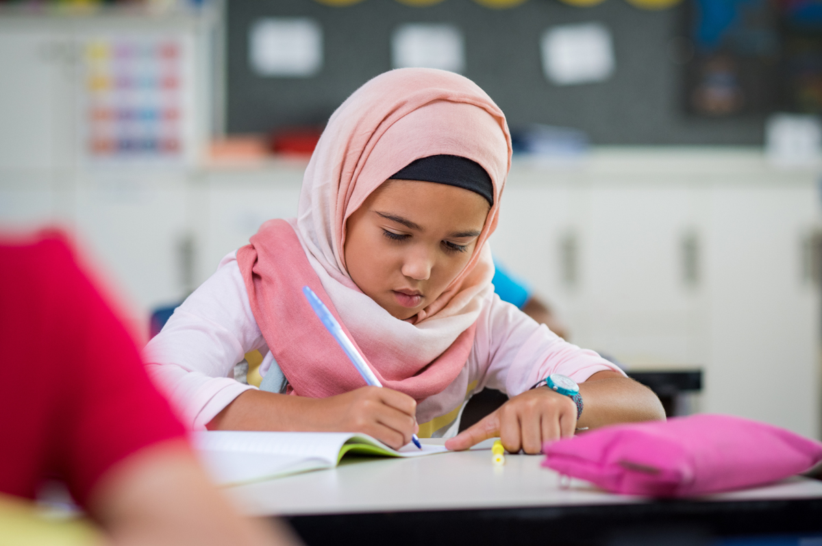 Young girl wearing hijab studying