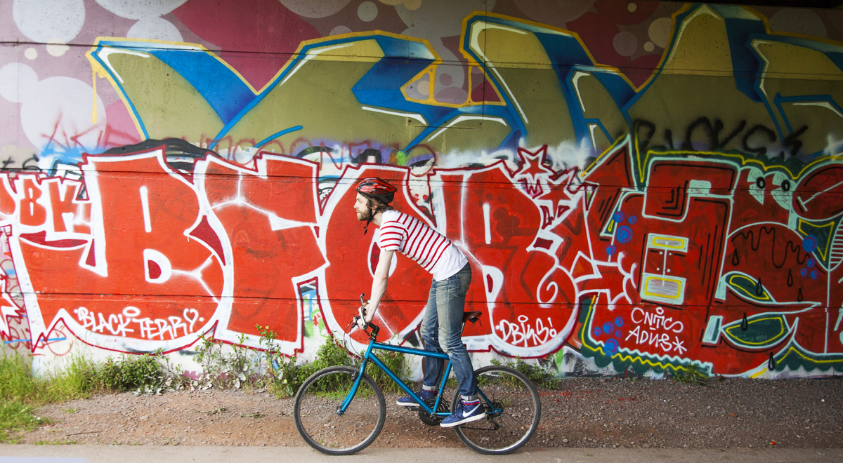A adult person on a bike with graffiti in the background