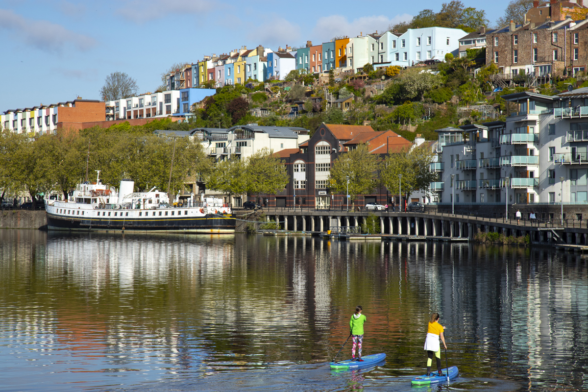 Harbourside paddleboarders and houses in the background