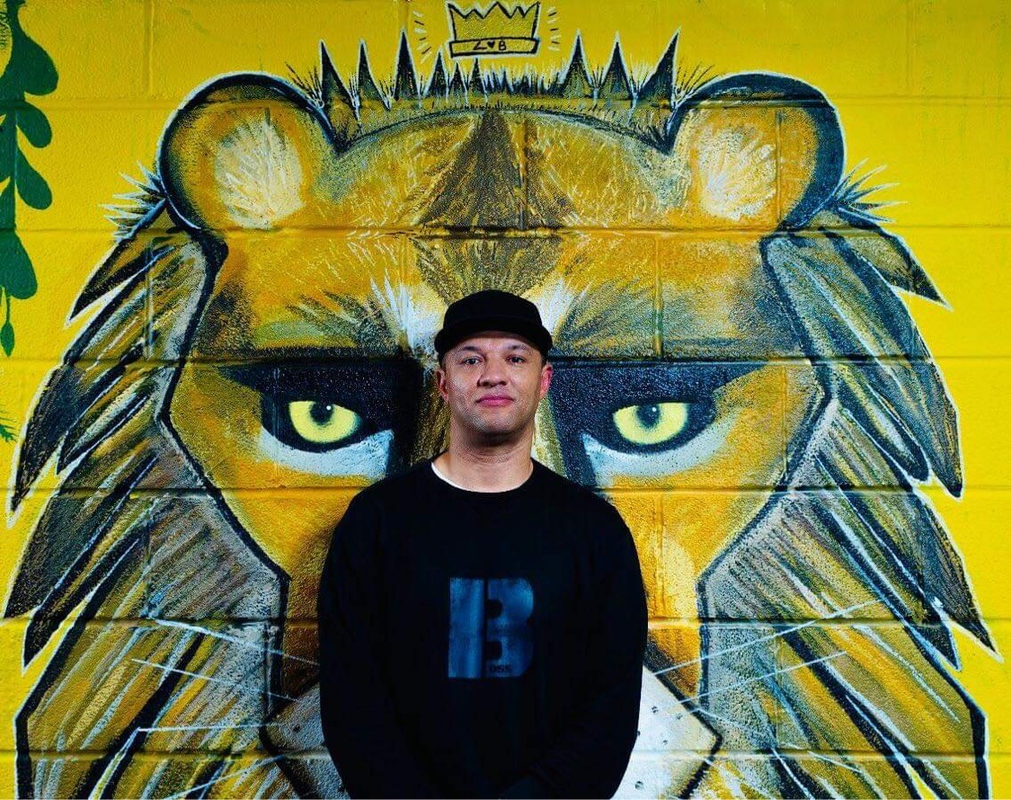 DJ Bunjy standing in front of street art depicting a lion
