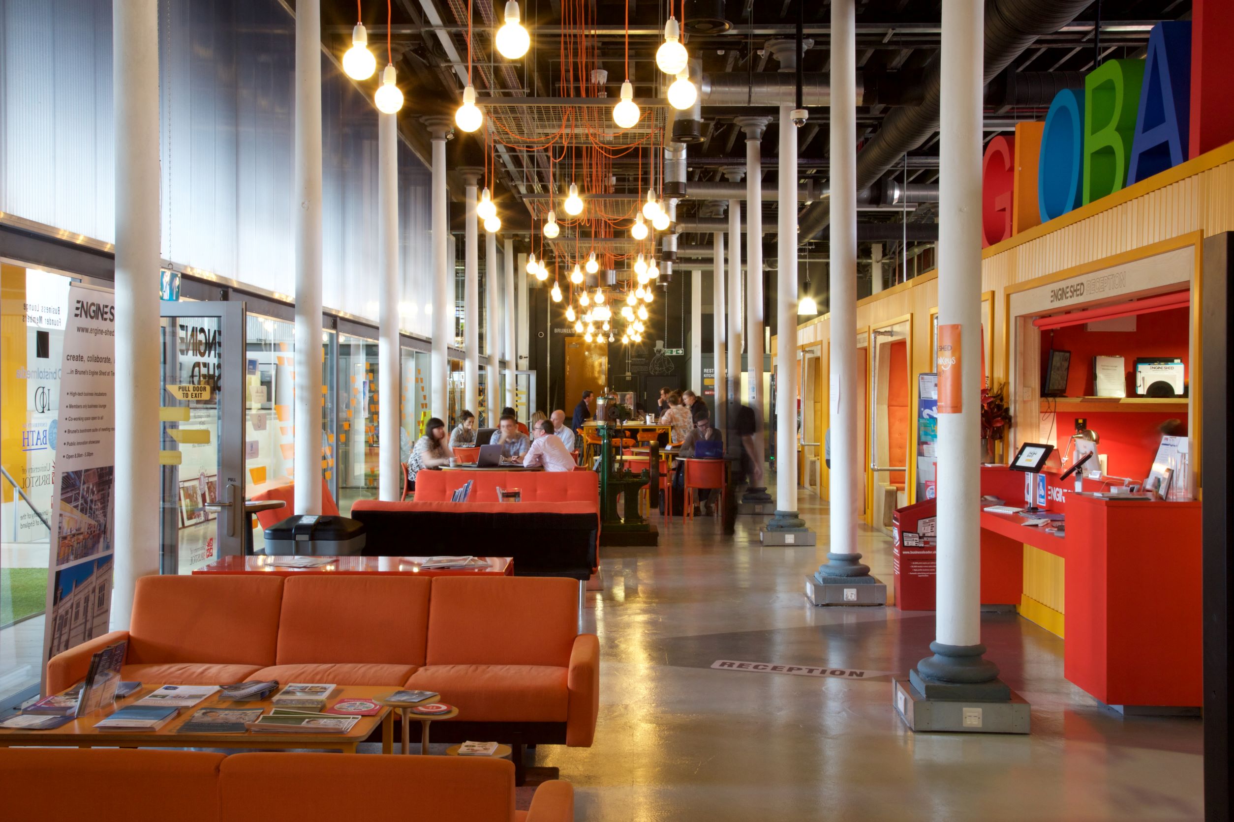 People sitting and working in the bright and colourful Engine Shed shared workspace